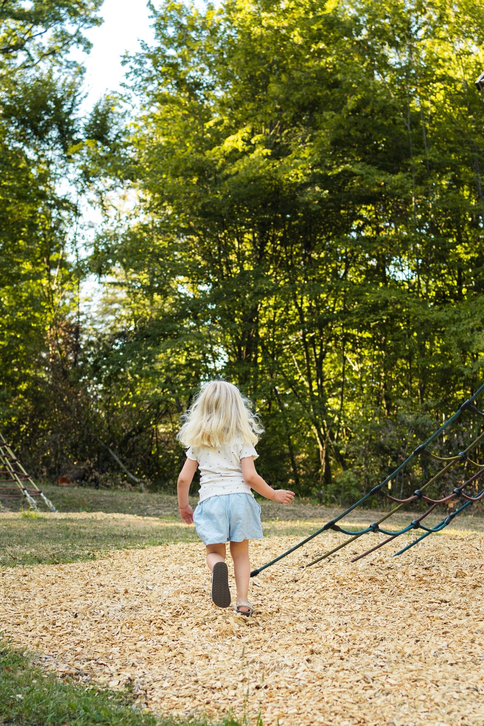 Kind läuft über den Spielplatz auf ein Klettergerüst zu